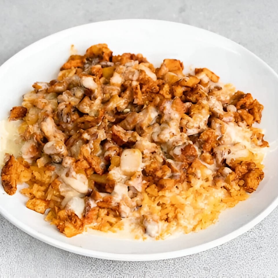 A white plate holds a generous serving of Mexican rice topped with chicken and melted cheese.