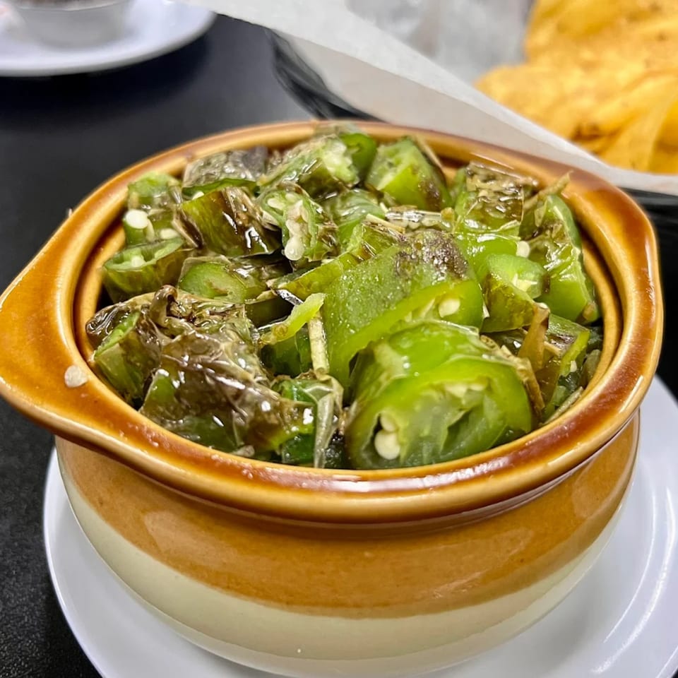 A brown and cream bowl filled with chopped green chiles, likely from Smack'n Tacos Taqueria & Bar.