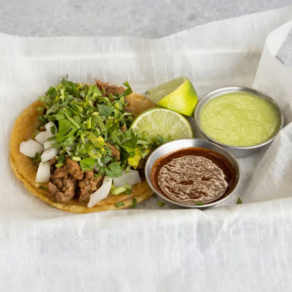 Smack'n Tacos' carne asada taco with cilantro, onions, lime, and two dipping sauces.